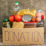 Cardboard box with the word donation written on it, filled with food