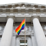 A gay pride flag on display in front of a government building