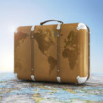 old suitcase on blurred world map and sky in background