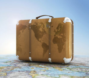 old suitcase on blurred world map and sky in background
