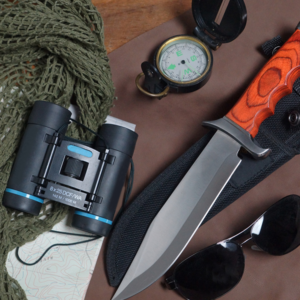 A collection of survival gear, including a large knife, binoculars and compass