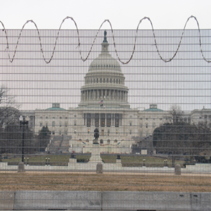 A view of the Capitol from behind a tall, barbed fence